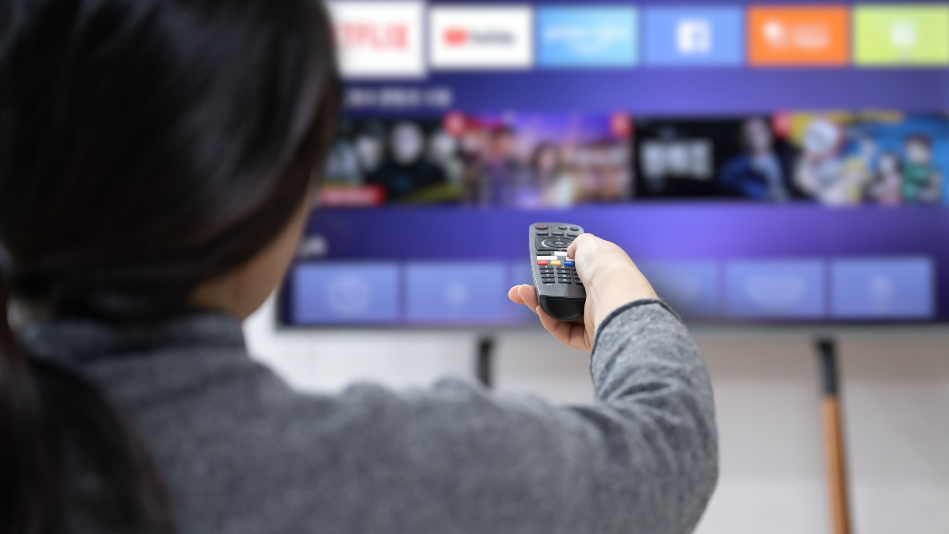 A woman experiences OTT service using a smart TV at home