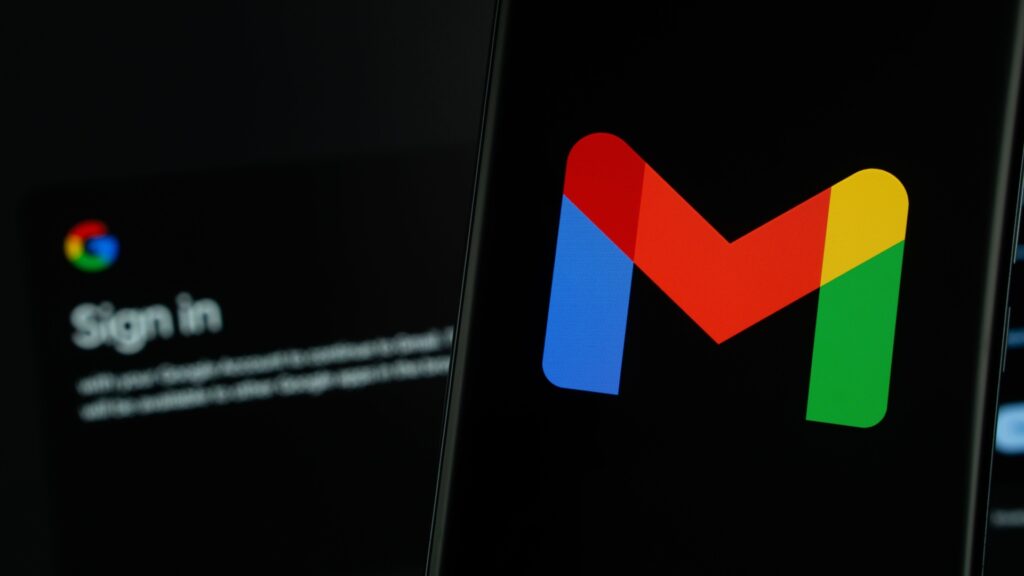 Gmail logo on smartphone and sign-in page on laptop