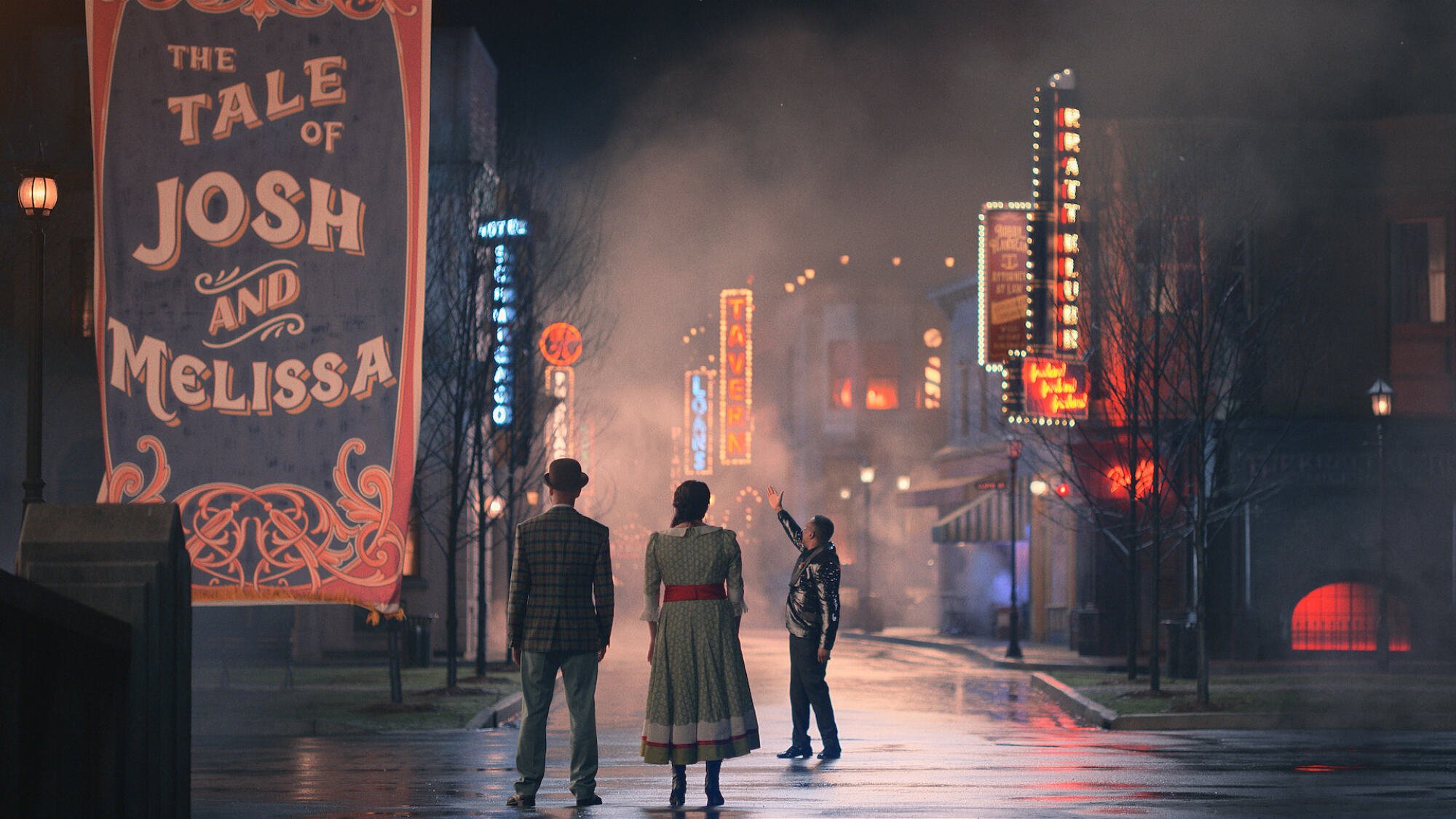Two people stand on the street outside a musical theatre-like town.