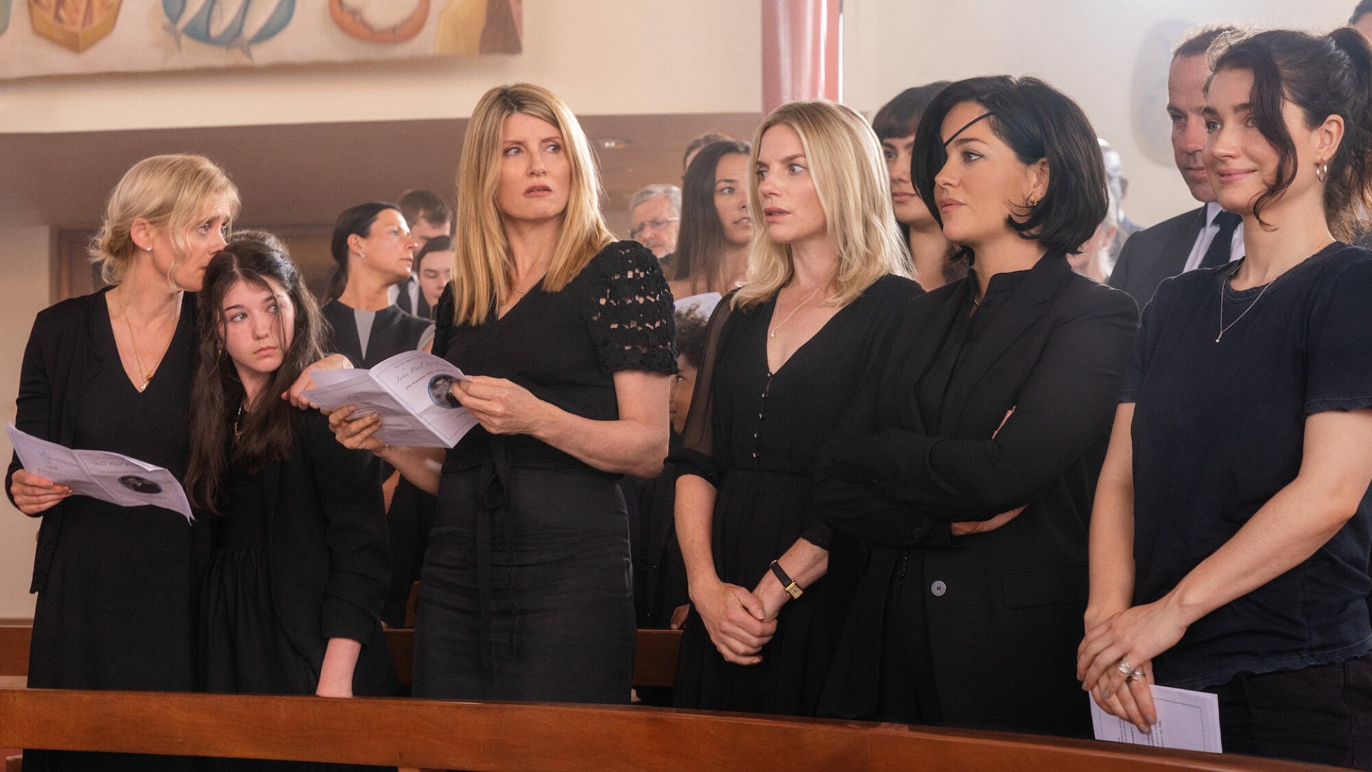 The cast of "Bad Sisters" in black attend a funeral.