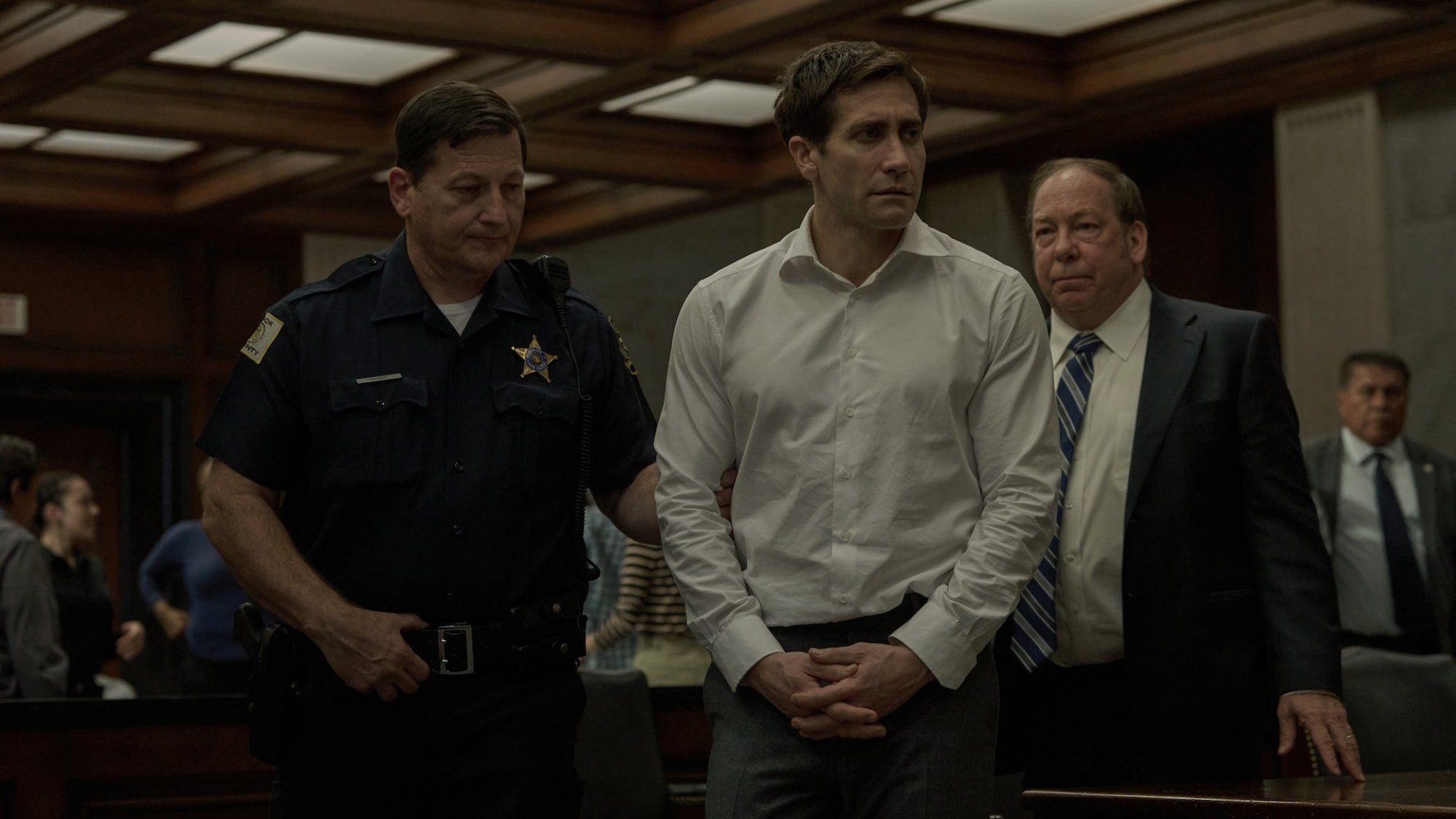 Jake Gyllenhaal and Bill Camp in "Presumed Innocent" standing in a courtroom.