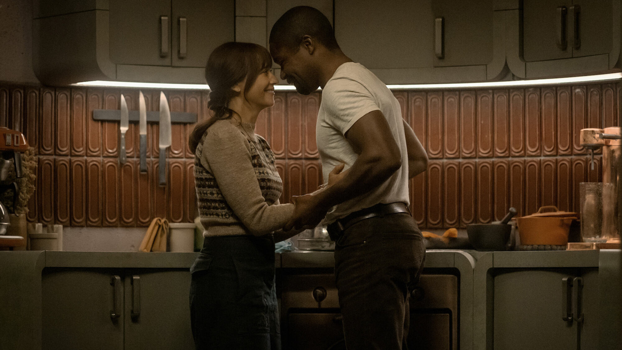 Rashida Jones and David Oyelowo stand with their foreheads touching in a futuristic kitchen in "Silo."