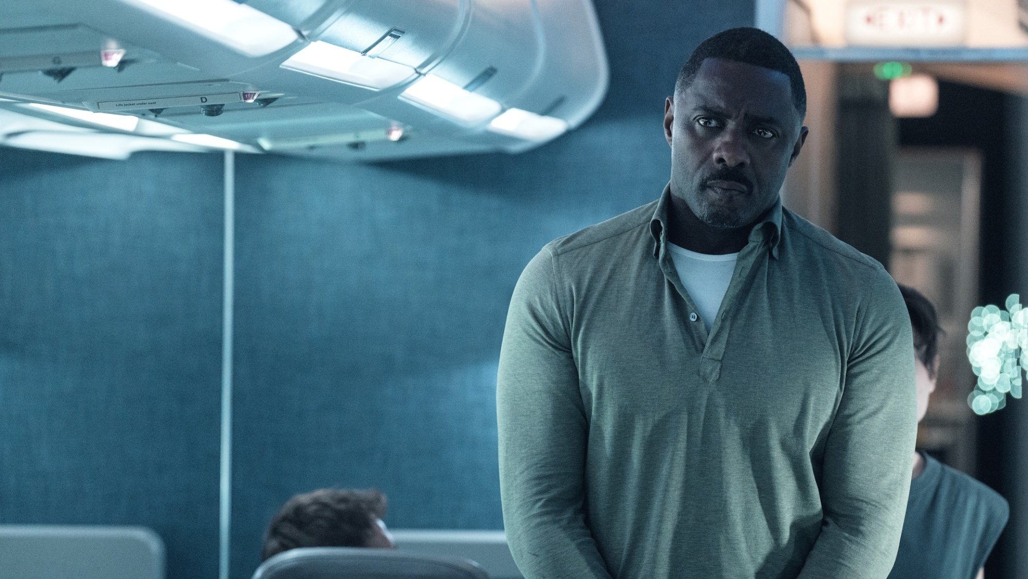Idris Elba stands in the aisle of a plane in "Hijack."