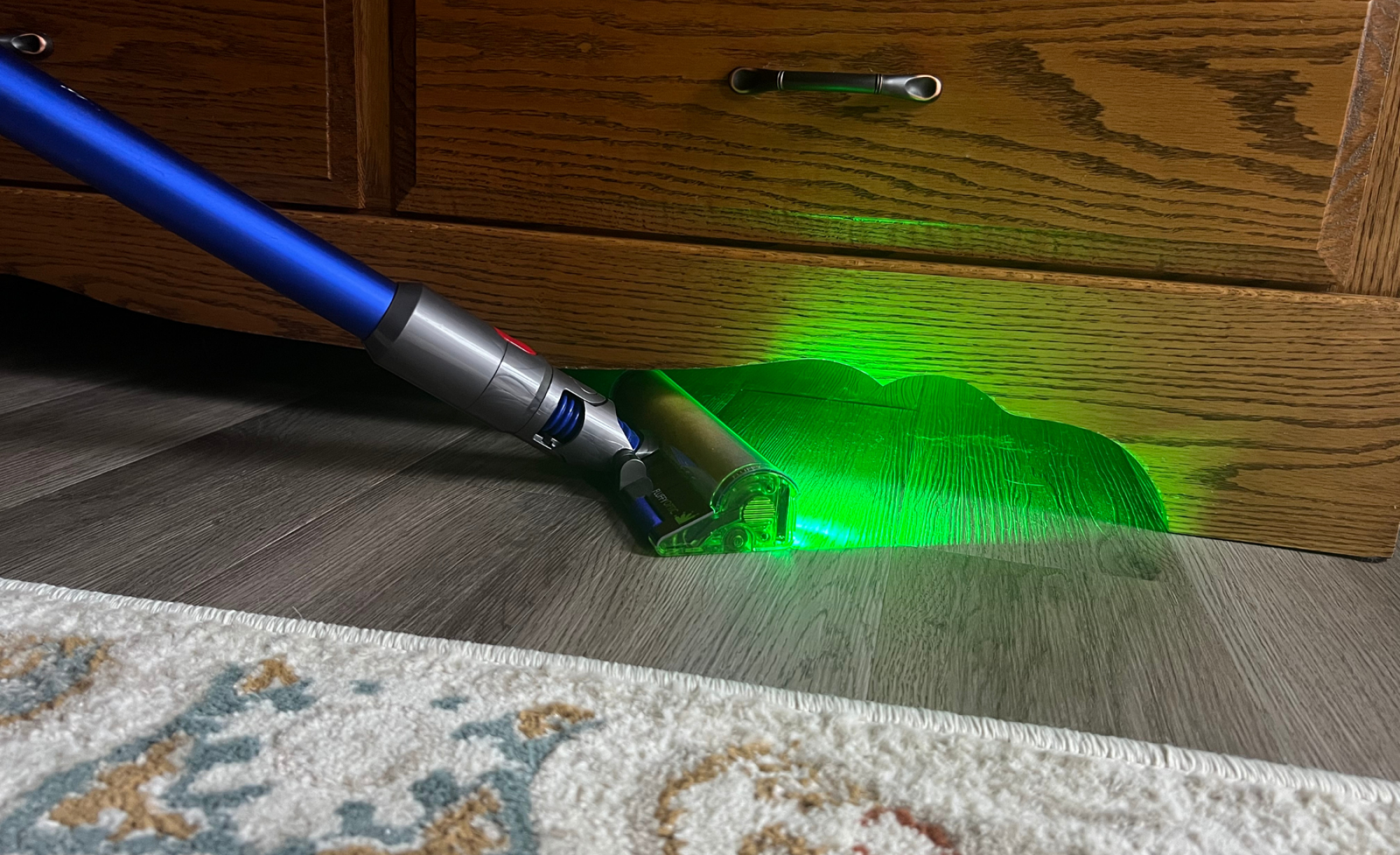 Dyson vacuum shining laser and cleaning wood floor under furniture