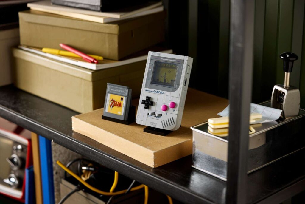 a flat lay of the lego game boy next to its accessories on a red surface
