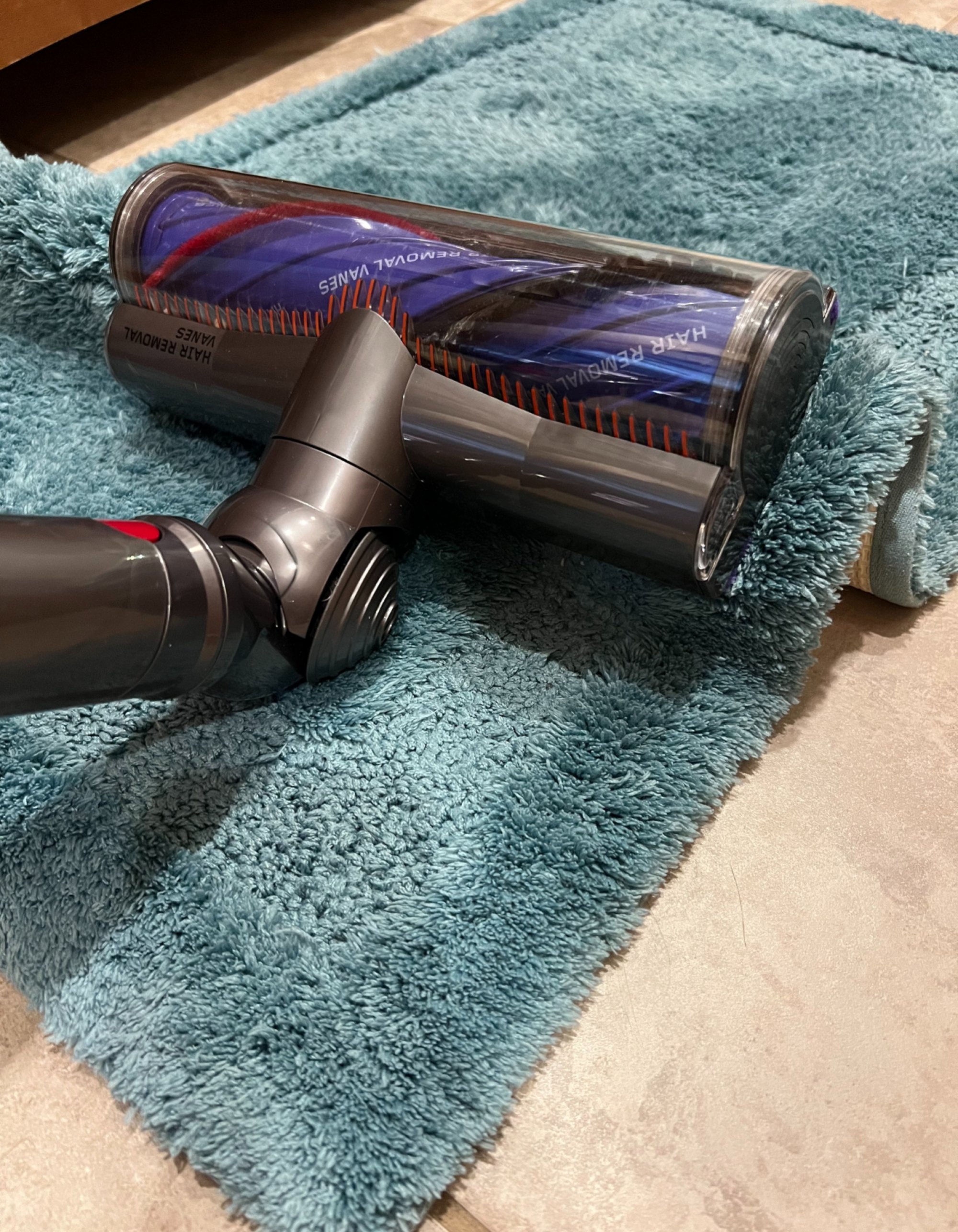 Dyson vacuum cleaning head sucking up blue rug