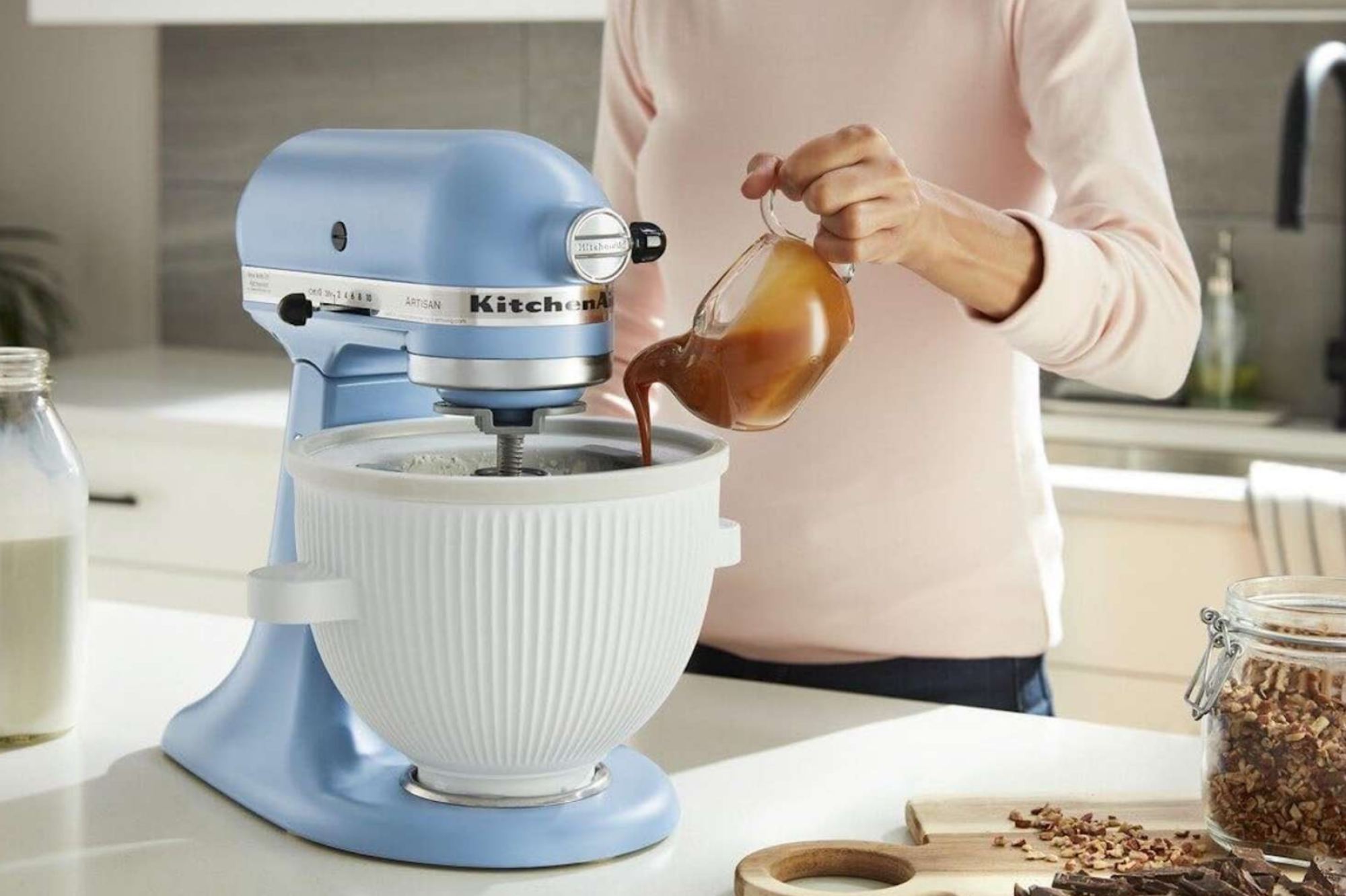 Person pouring ingredient into KitchenAid mixer with ice cream attachment