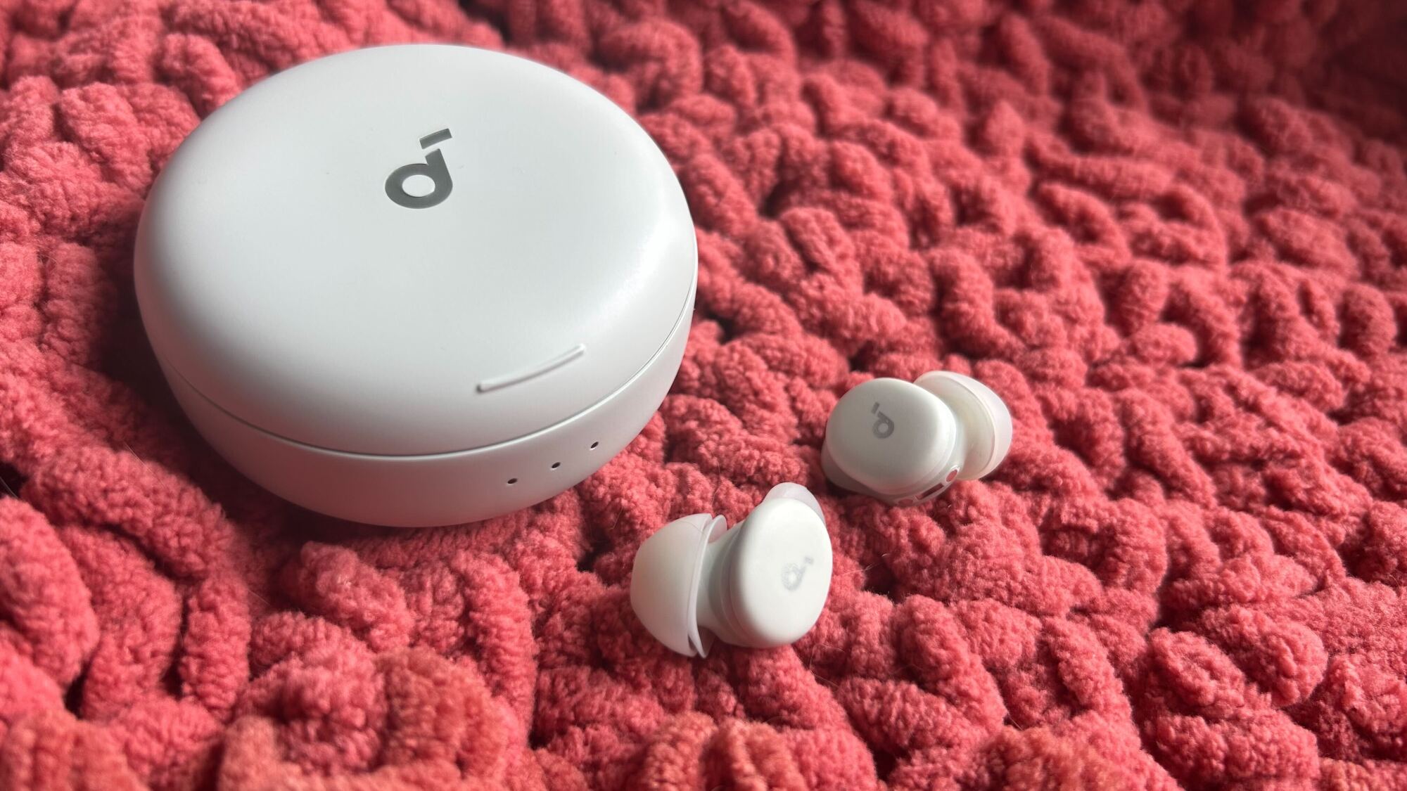 sleep a30 earbuds and case on red blanket
